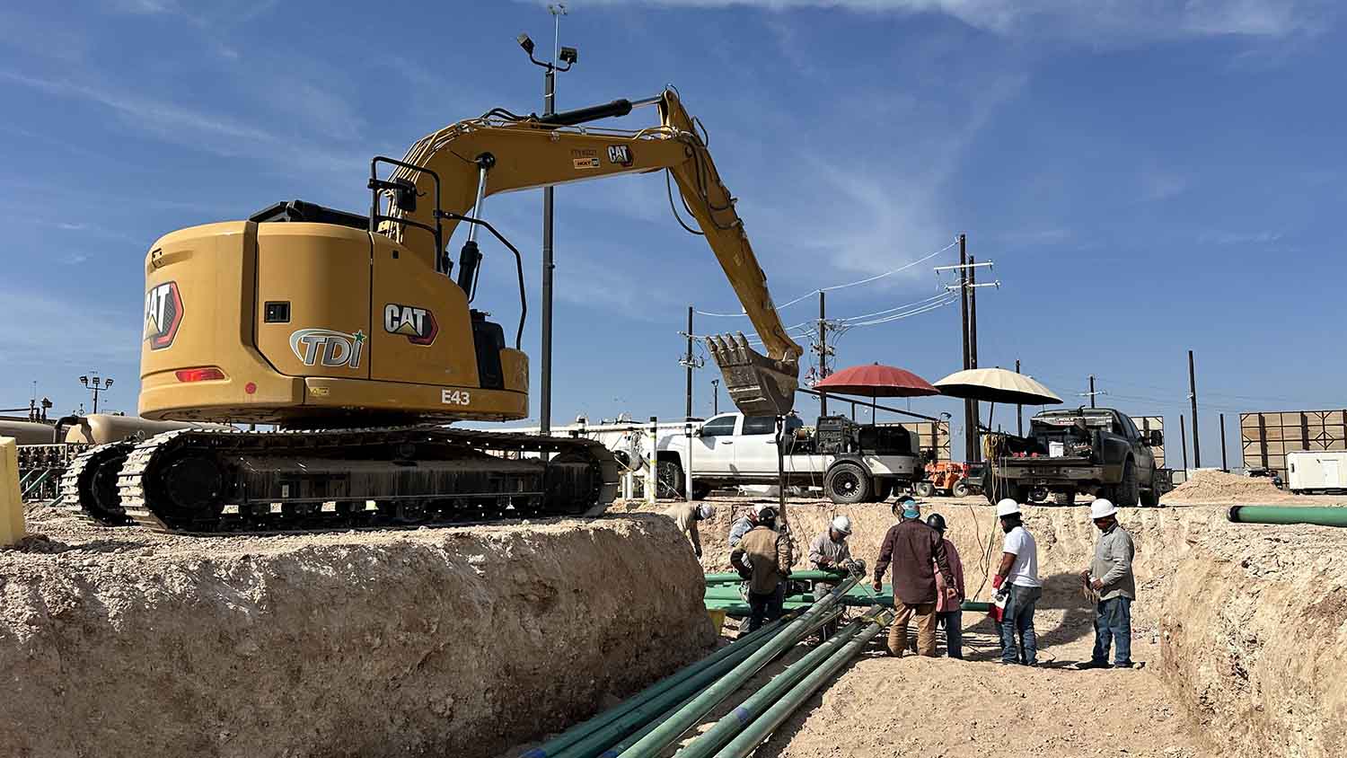Pipefitting crew making a flowline tie-in connection in an open trench